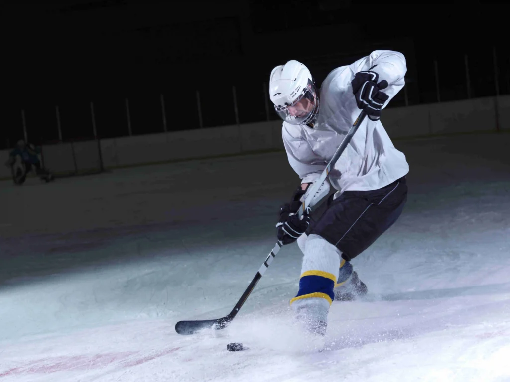 Hockey player making a powerful turn on dark ice rink during off-season performance training